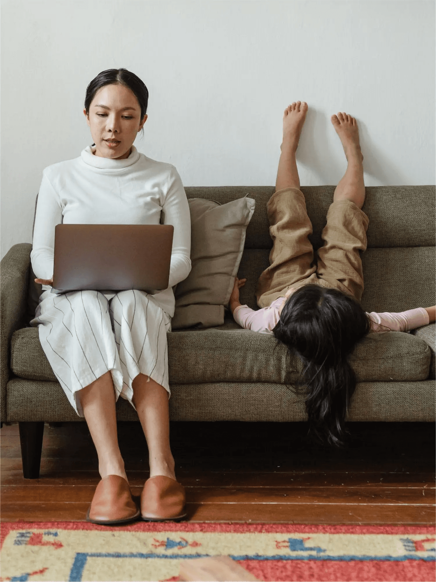 Content marketer working from home, with child doing gymnastics in the sofa.